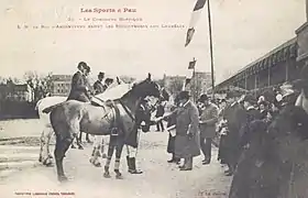 Photographie d'un homme félicitant des cavaliers.