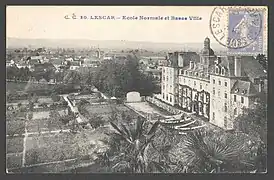 Photographie en noir et blanc d'un bâtiment imposant et d'un village en contrebas.