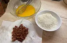 Photo d'œufs battu dans un saladier, de fromage râpé dans une assiette creuse et de morceaux de viande dans une assiette