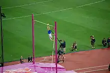 Photographie de Renaud Lavillenie en phase ascendante lors d'un saut à la perche