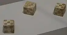 Photographie de trois dés à six faces taillés dans de l'os.