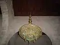 Gros plan sur un petit lustre ouvragé de l'une des nefs secondaires de la salle de prière. Il présente un plateau circulaire finement ajouré, surmonté de merlons en dents de scie.