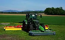 Ensemble de trois faucheuses-conditionneuses à disques entraîné par le même tracteur. Le conditionneur écrase l'herbe pour diminuer le temps de fanage. Autriche, 2018.