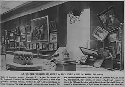 Photographie montrant les impactes des obus allemands dans la salle consacrée à la Galerie Henry Vasnier au Musée des Beaux-Arts de Reims. La cimaise présente un trou et plusieurs tableaux tombent ou sont en train de tomber, parfois même défaits de leur cadre.