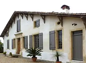 Une façade de demeure de maître landaise avec une porte d'entrée remarquable.