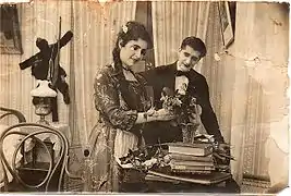 Photo en noir et blanc montrant une femme recevant des fleurs, un homme à ses côtés lui sourit