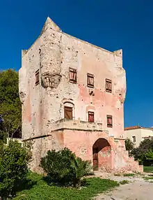 Grand bâtiment carré rose, avec des échauguettes à chaque coin et un escalier sur le devant