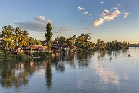 Berge du Mékong avec des habitations sur pilotis, des arbres et des nuages à l'heure dorée, vue depuis le pont reliant Don Det à Don Khon. Décembre 2021.