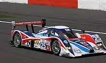 Photographie d'une voiture de sport-prototype, bleue, blanche et rouge, vue de trois-quarts avant, sur une piste.