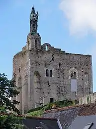 Photographie en couleurs d'une tour carrée surmontée d'une statue.
