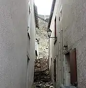 Photographie en couleurs d'un massif de maçonnerie bouchant une ruelle.