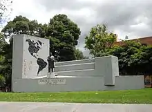 Photographie d'un monument constitué d'une pierre sur laquelle sont peints les deux continents américains et d'une statue d'un homme en-dessous duquel il est inscrit : « Americo Vespucio 1452-1512 ».