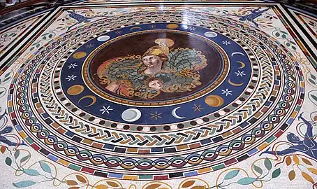 Mosaïque colorée composée de motifs circulaires, au centre la figure d'Athéna casquée surplombe le masque de Méduse.