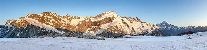Derrière un plateau de neige une barrière de montagnes rocheuses.