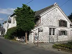 Maison dont un pan entier est recouvert de tuiles dans un style namako à Matsuzaki.