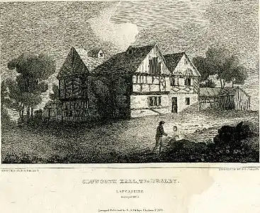 Un homme conversant avec une femme, assis sur un rocher au premier plan au centre à droite ; Cluworth Hall en arrière plan.