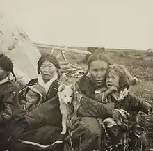 Photographie de deux femmes et de leurs deux enfants indigènes (Kètes) avec un chiot blanc devant leur tente.