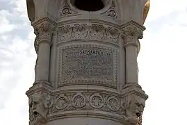 Inscription : Georges SAUMANDE MAIRE / Charles SEGARD Colonel en retraite / Commandeur de la Légion d'honneur / Premier adjoint / Edmond LACOUT Conseiller / municipal délégué aux fonctions de / deuxième adjoint, sur un côté du piédestal de la statue, fontaine de la place Plumancy.