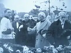 Hommes et enfant de chœur devant un cercueil.