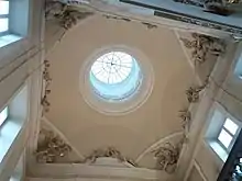 Un plafond avec un lanternon et des sculptures autour.