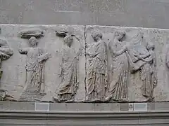 Frise située à l'est représentant trois femmes, un homme et un enfant tenant un tissu