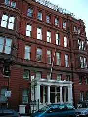 Immeuble en briques au portique d'entré blanc encadré de piliers avec deux colonnes au milieu, vu en légère contre plongée, légèrement à gauche.