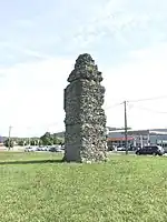 Photographie en couleurs d'une tour ; au second plan passe une route.