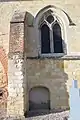 Contrefort, fenêtre gothique et porte basse murée.