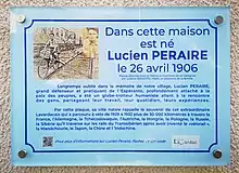 Plaque bleue en plexiglas portant un petit texte et deux photos de Lucien Péraire.