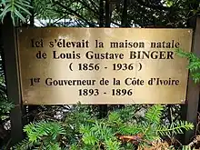 Plaque en laiton dans la haie de tuyas qui entoure la maison natale de Louis-Gustave Binger.