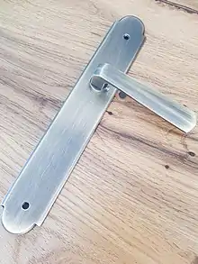 Poignée de porte en laiton sur une plaque longitudinale (plaque de propreté longue)