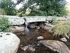 Vieux pont traditionnel fait de grosses dalles de pierre sur le ruisseau de Grezettes.