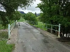 Pont à rambarde en fer forgé aux extrémités en forme de balustres.