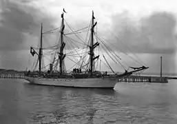 Photographie en noir et blanc d'un navire sortant d'un port.