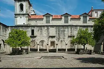 Photographie d'un cloître situé devant une église vue latéralement.