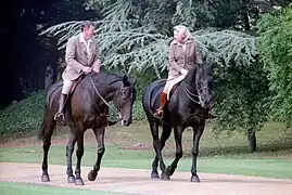 Photographie d'un homme et d'une femme, tous deux à cheval, en train de discuter.