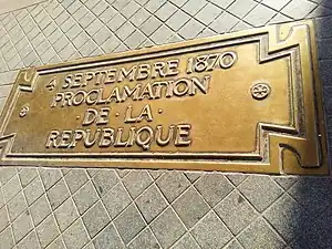 Plaque en bronze installée au centre d'un sol pavé.