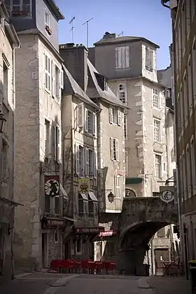 Photographie en couleurs en couleurs d'une petite rue sur laquelle passe l'arche en pierre d'un pont.
