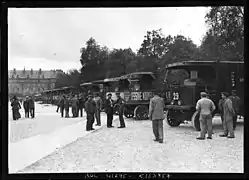 Photo noir et blanc avec file de camions le long d'une rangée d'arbres.