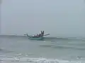 Le bateau revient à la plage après avoir posé le xalavar en mer. On aperçoit derrière le bateau le câble du filet.