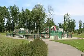 Aire de jeux multisports entourée de barrières en bois.