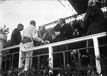 Photo d'un homme, Robert Benoist, serrant les mains des officiels de la course après une victoire.
