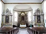 Vue intérieure de la nef vers le chœur avec les autels.