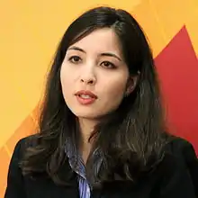 Portait d'un femme sur un fond rouge et jaune, en train de parler.