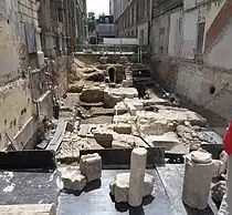 Vue générale du chantier de fouilles en juin 2013. Niveaux successifs : zone romaine, terre agricole du cloître avec une pierre tombale encore en place, début du chœur, extrémité de la nef, au fond : égout haussmannien (1860).