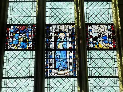 Le vitrail central représente saint Quentin dans un édicule gothique. Le vitrail de gauche, plus petit, présente l'intérieur de la maison d'un drapier. Le tailleur est en train de couper une pièce d'étoffe rouge tandis que sa femme, assise à ses côtés, travaille sur une pièce d'étoffe bleue. Sur le vitrail de droite, de même taille que le précédent, deux portefaix déchargent leur fardeau devant un bâtiment, que l'historien Georges Lecocq suppose être l'ancienne halle au blé de Saint-Quentin