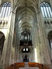 Grand espace sous des voûtes soutenues par des piliers. Au fond de l'image, un buffet d'orgue en bois.