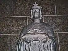 Statue de bronze d'un roi portant une relique sur un coussin.