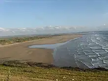 Plage de sable beige vue depuis une colline.