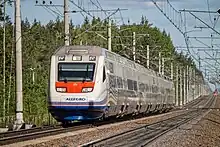 Train blanc photographié de devant sur une ligne ferroviaire électrifiée.